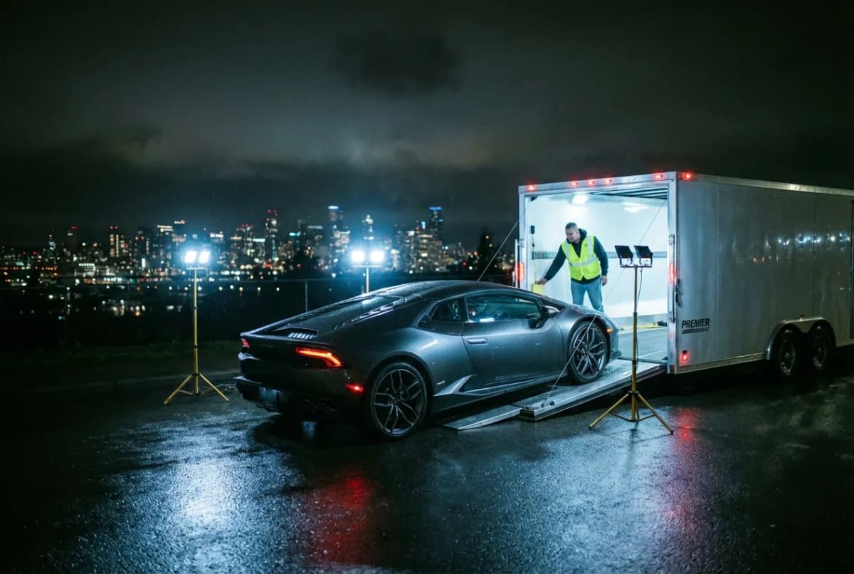 NY to LA enclosed shipping — vehicle loaded into sealed trailer under lights for cross-country delivery