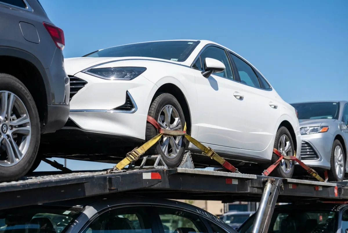 Car shipping cost by distance — Hyundai Sonata sedan on open carrier traveling interstate highway